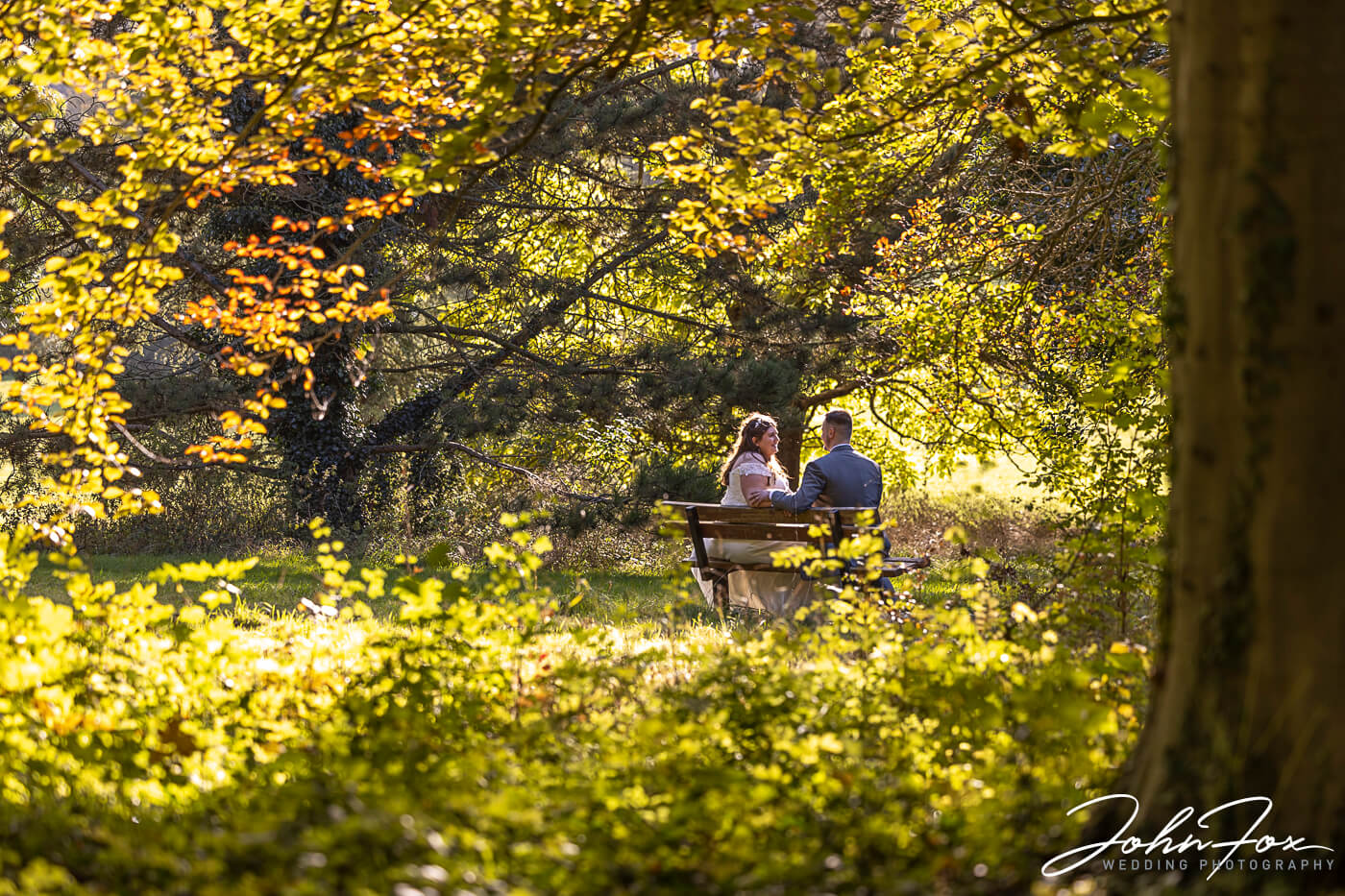 Bride and groom sitting in the grounds and woodland at Magnolia Park on their wedding day.