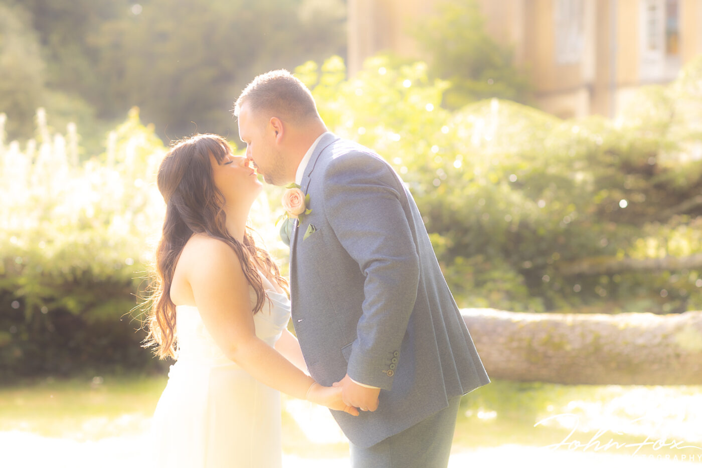 Bride and groom share a kiss in the grounds of Missenden Abbey
