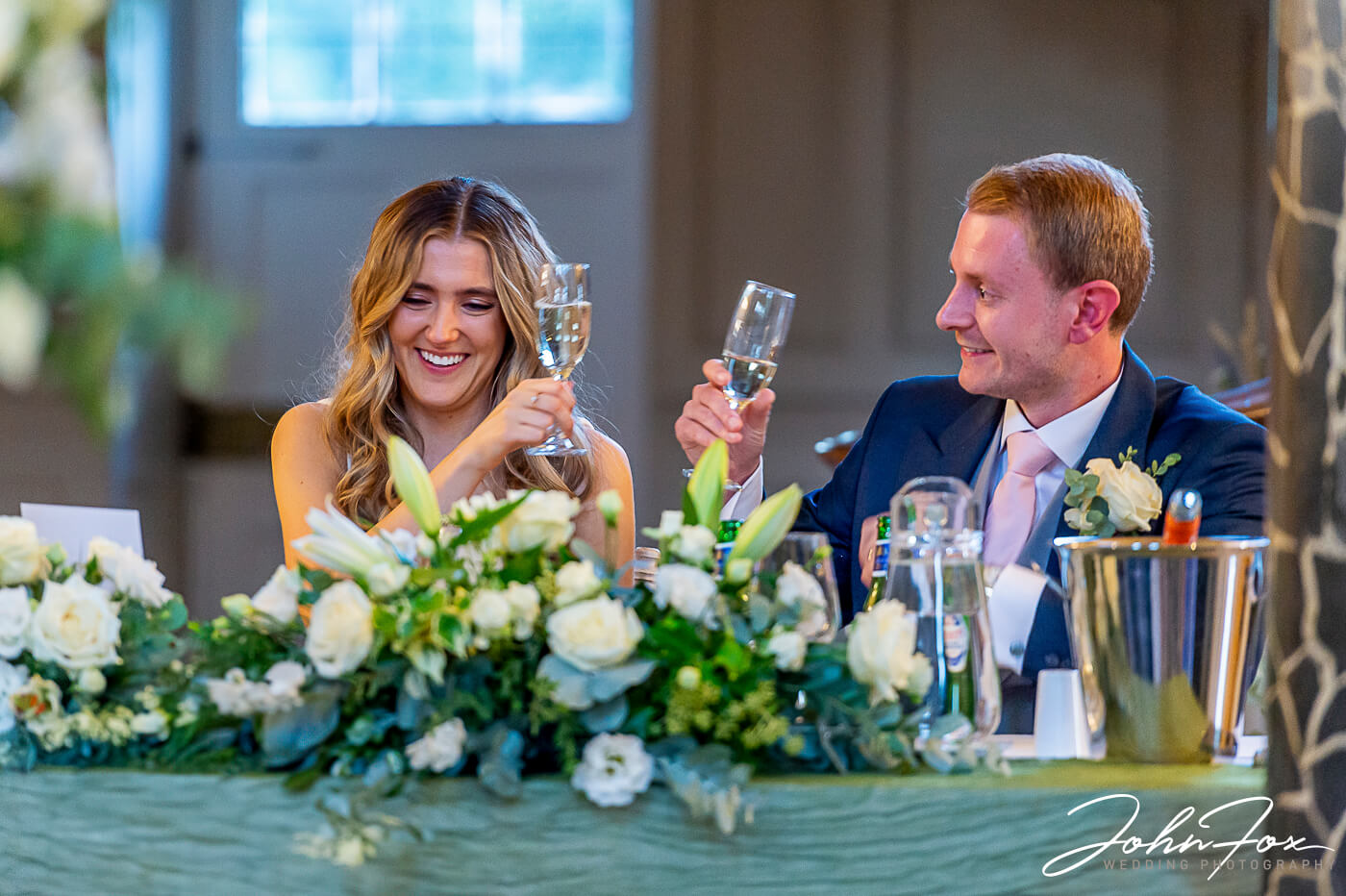 Lorna and James toasting their wedding with glasses of bubbly. Wedding photographer at Chicheley Hall, Buckinghamshire.