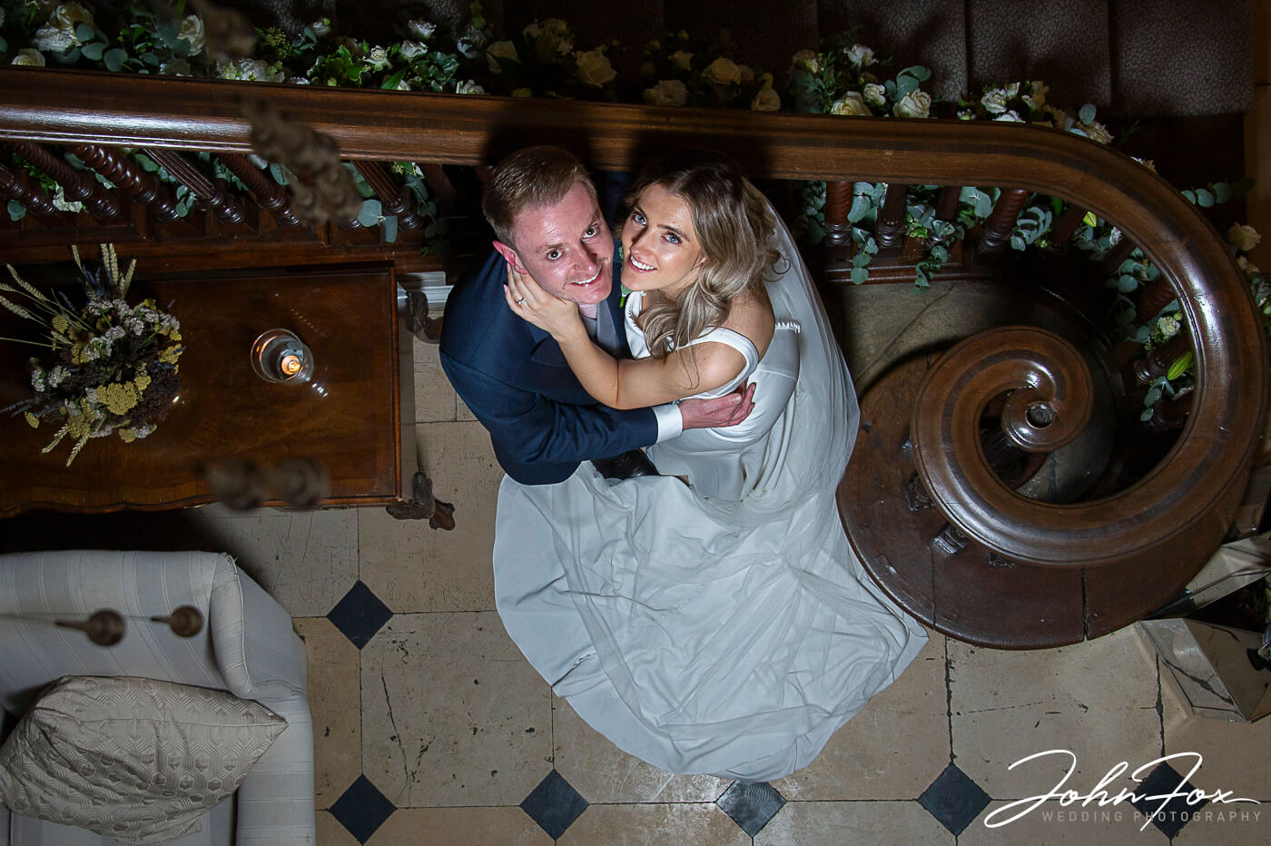 Lorna and James sitting by the grand staircase inside the hall at this wonderful Buckinghamshire wedding venue