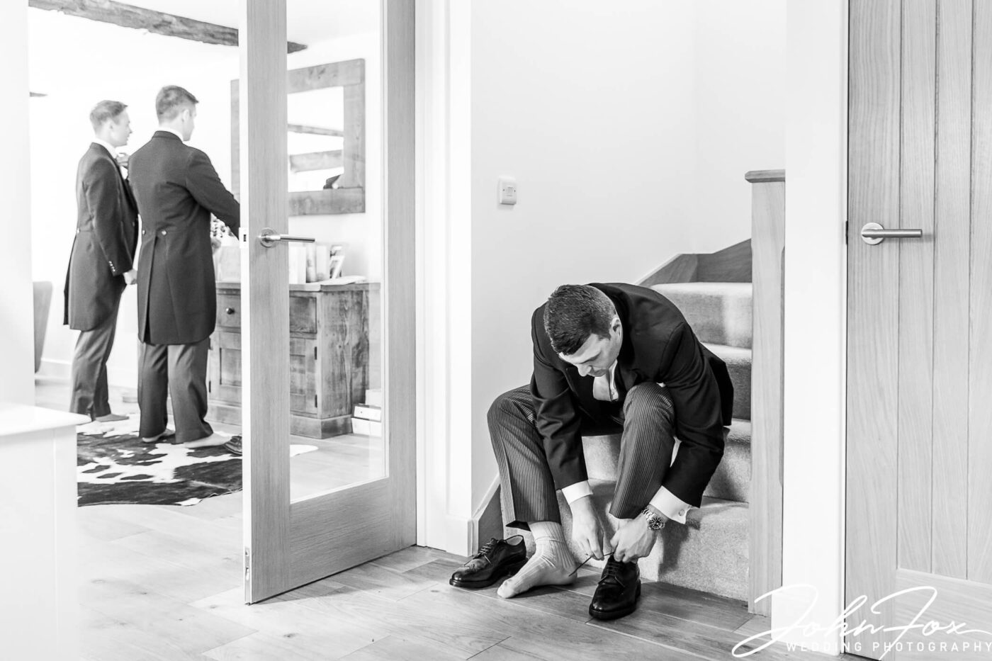The best man tying his shoelaces on the stairs. Photo by John Fox Wedding Photography