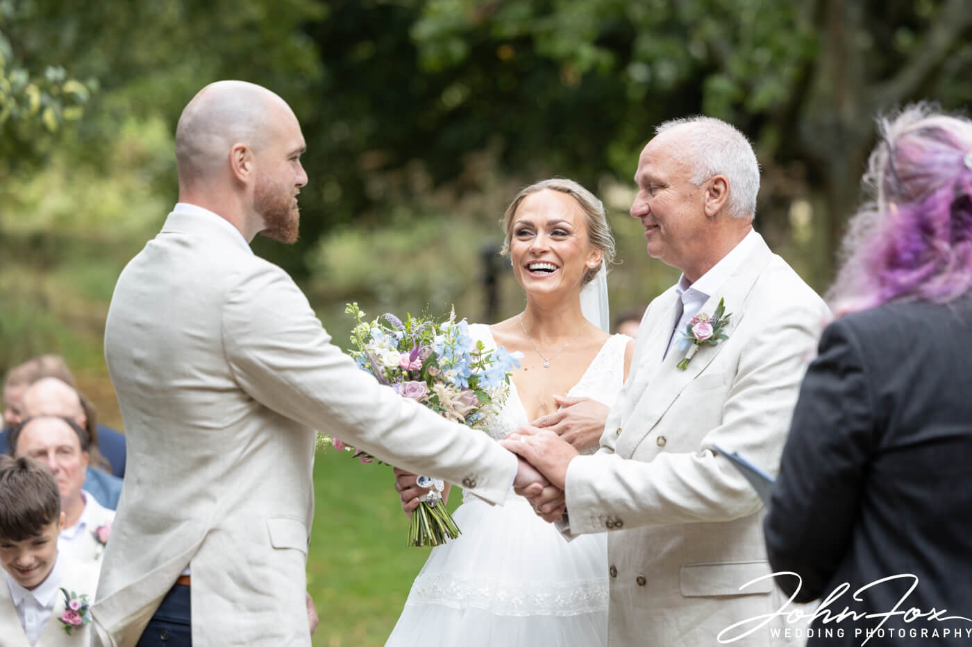 The father of the bride gives his daughter away. Photo by John Fox Wedding Photography