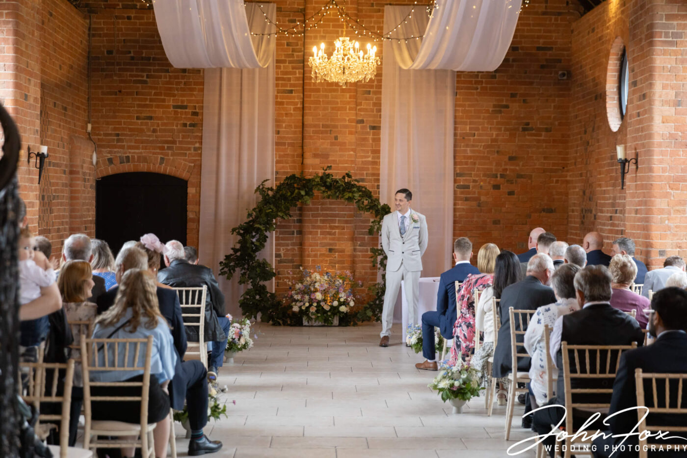 The groom waiting for the bride at the wedding ceremony at Meadow Barn, Stratford-upon-Avon