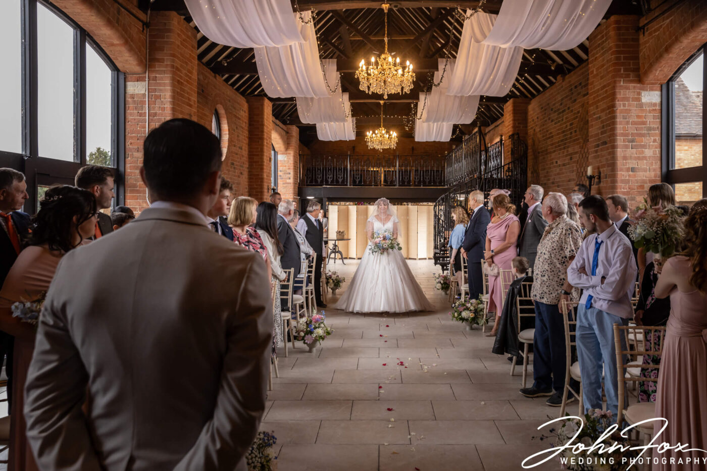 The bride walking up the aisle at Meadow Barn, Stratford-upon-Avon. Image by John Fox.