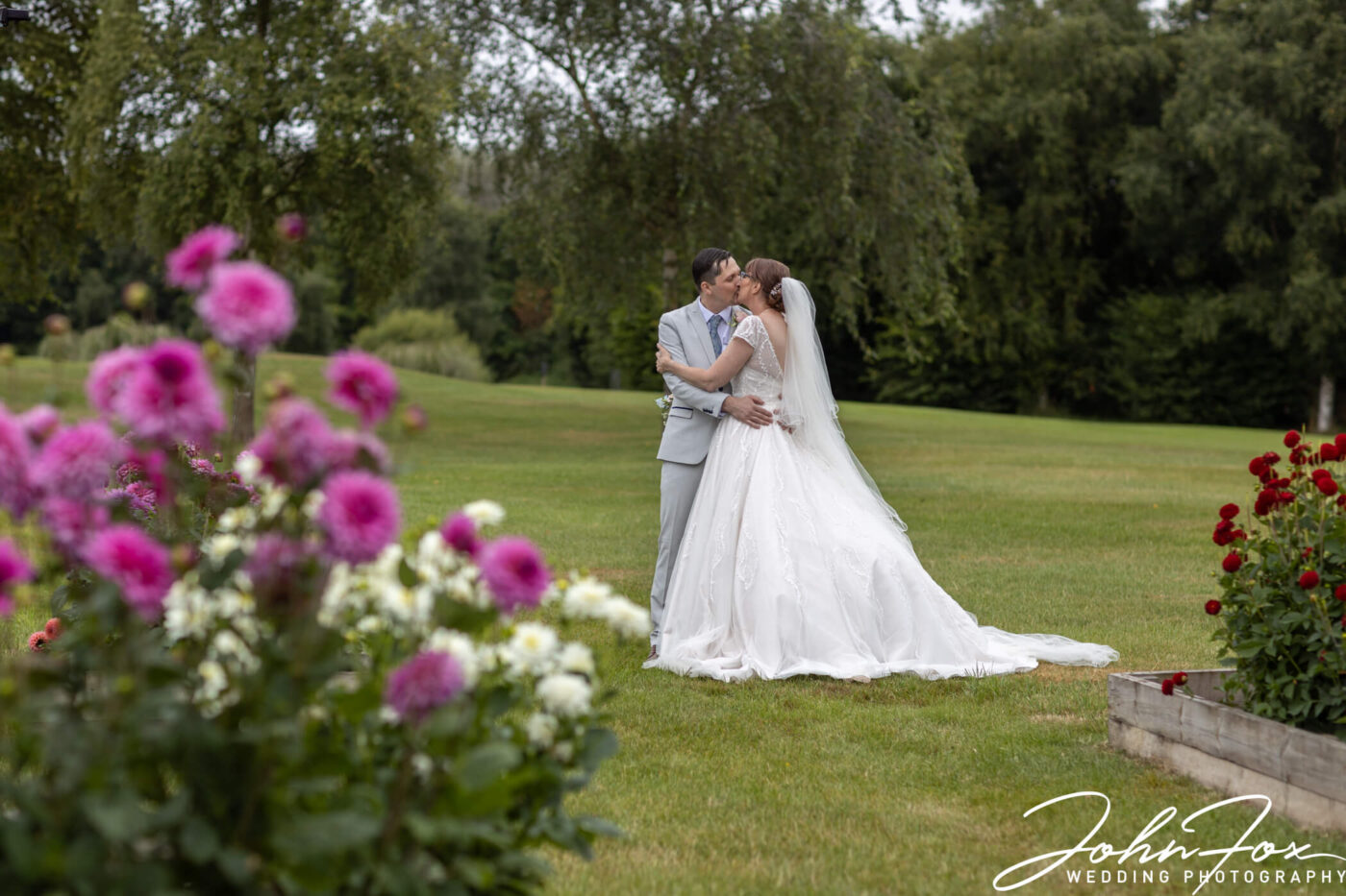 The wedded couple kiss in the grounds at The Stratford Park Hotel